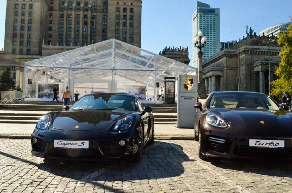 Porshe Cayman S oraz Porshe Panamera Turbo przed halą namiotową w centrum Warszawy